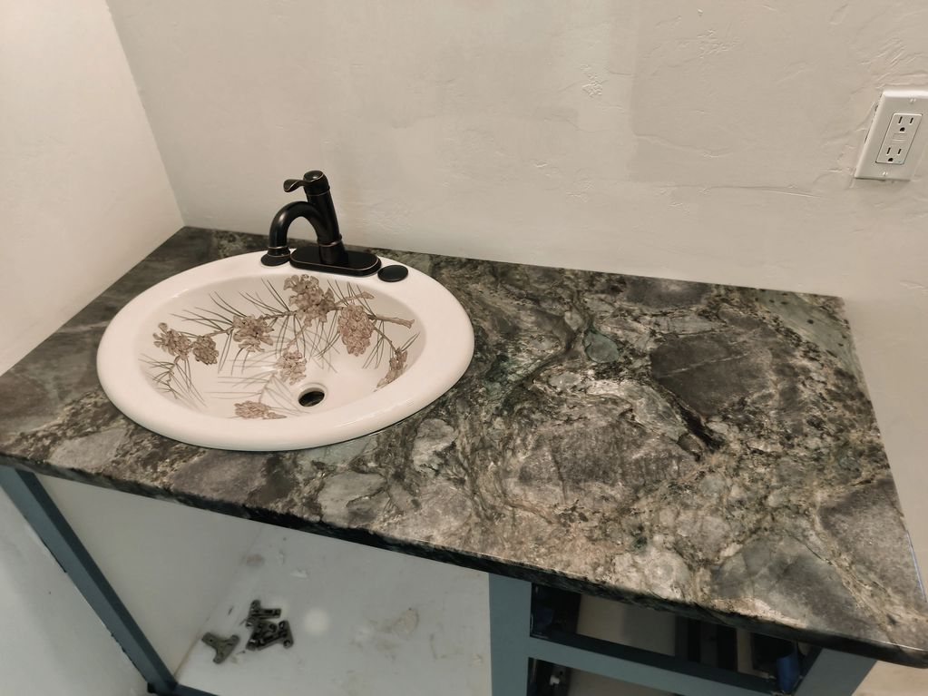 Bathroom sink with floral ceramic basin and dark granite countertop.