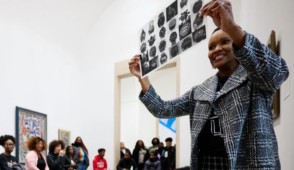 Woman presenting black-and-white artwork in front of seated audience.