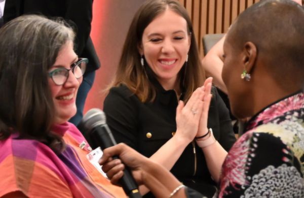 Three women engaged in a lively conversation, one holding a microphone.