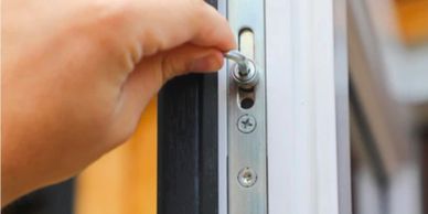 Hand unlocking a door lock with a key.