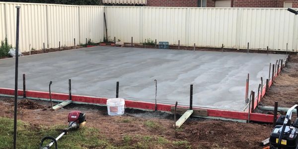 Freshly poured concrete slab in a backyard under construction.