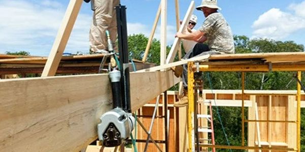 Workers assembling wooden structure on a sunny day at a construction site.