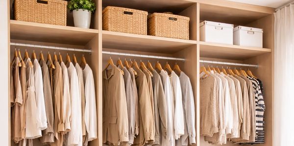 Organized beige wardrobe with clothes, shoes, and wicker baskets.