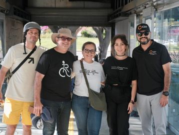 Cinco personas posan juntas en un espacio público cubierto.