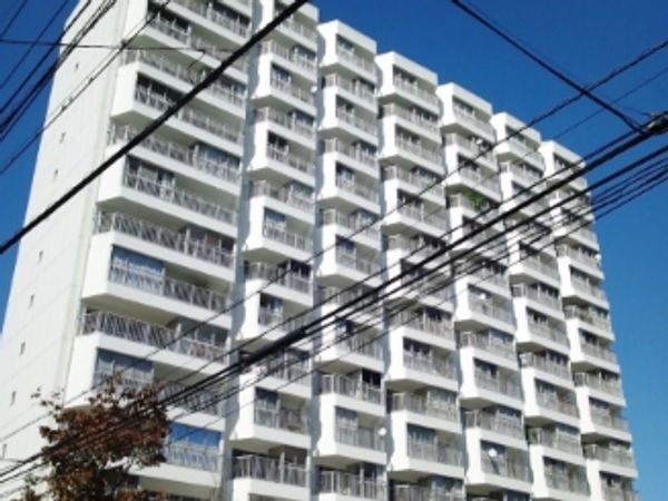 Tall white residential building under clear blue sky with overhead wires.