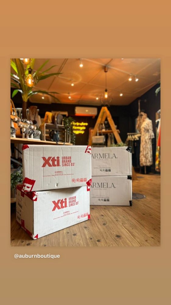 Stacked branded boxes inside a boutique with warm lighting and wooden flooring.