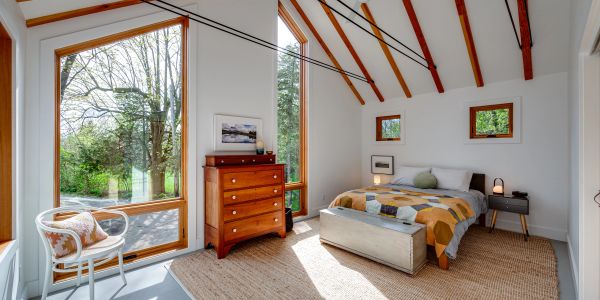 Bright bedroom with wooden furniture and large windows.