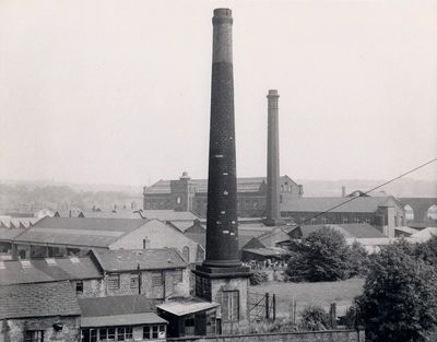 Black and white photo of tall mill chimneys surrounded by low buildings