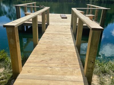 Wooden dock extending over calm water with simple railings.