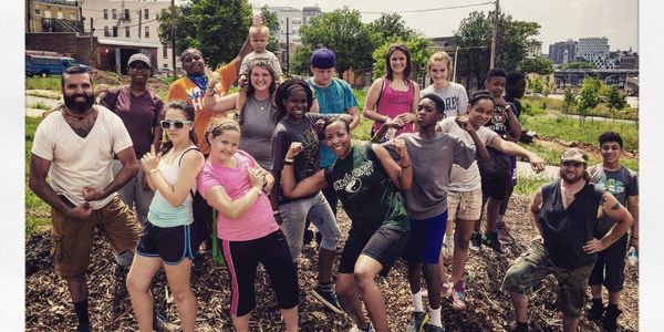 A diverse group of people posing outdoors in a garden or park.