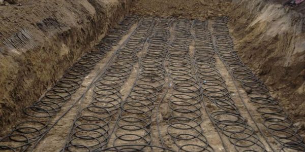 Coiled tubing arranged in an excavated trench for underground installation.