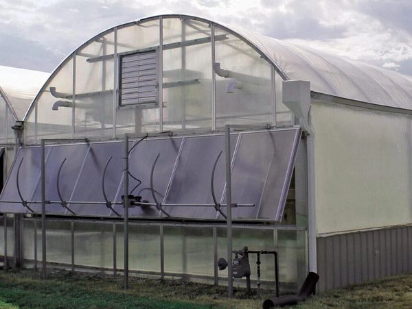 A modern greenhouse with solar panels and ventilation system.