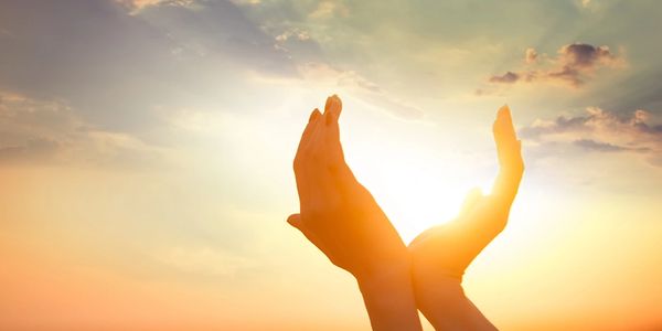 Hands cradling the bright sun during a beautiful sunset.