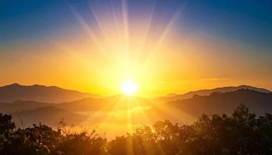 Bright sunrise over misty mountains and trees.