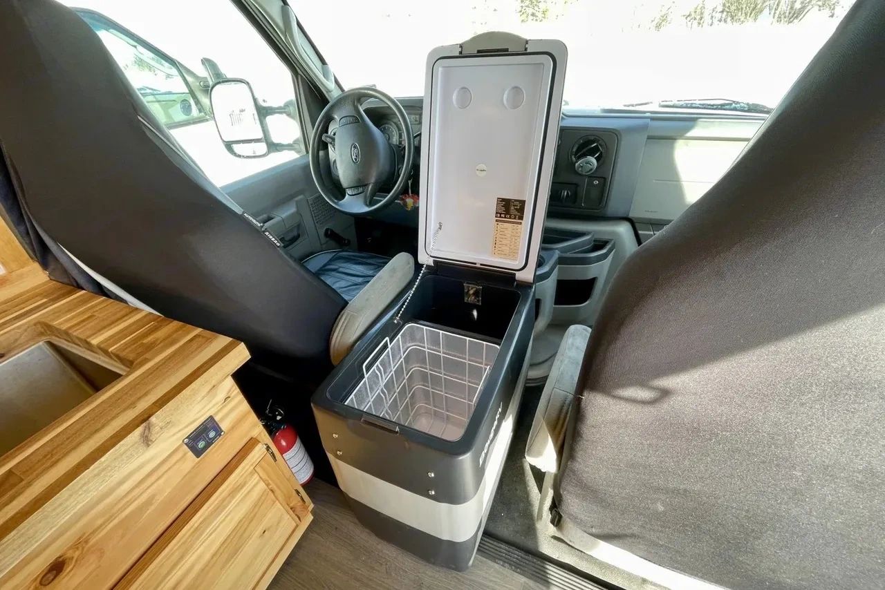 Open portable fridge inside a vehicle between two seats.