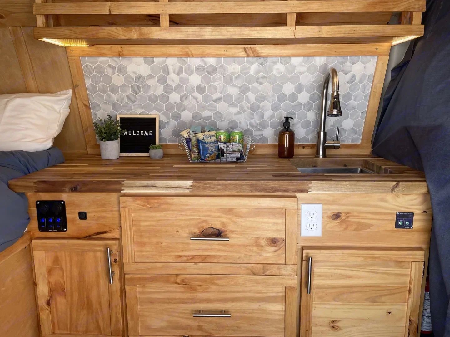Compact wooden kitchenette with hexagonal tile backsplash and cozy decor.