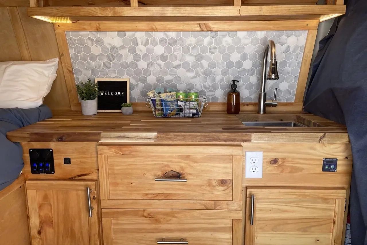 Cozy wooden kitchenette with hexagonal tile backsplash and welcome sign.