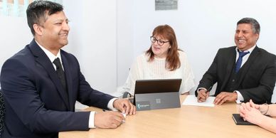Three professionals smiling during a business meeting.