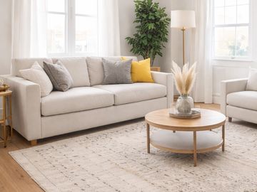 Bright living room with beige sofa, round wooden coffee table, and natural light.
