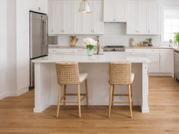 Modern white kitchen with wooden stools and a central island.
