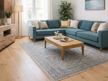 Cozy living room with teal sectional sofa and wooden coffee table on patterned rug.
