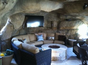 Cozy cave-themed outdoor lounge with sectional sofa and fire pit.