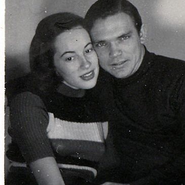 Black and white photo of a young couple posing closely together.