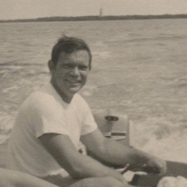 A man smiling while sitting in a boat on the water.