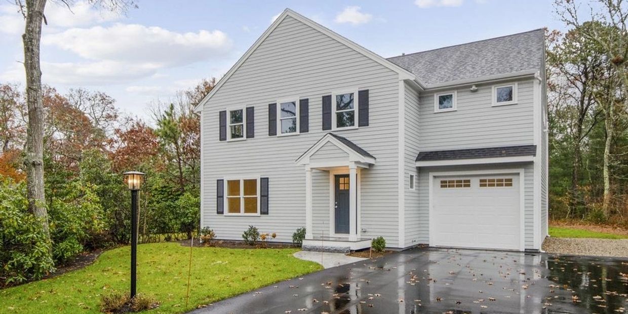 A modern two-story house with a white exterior and wet driveway.