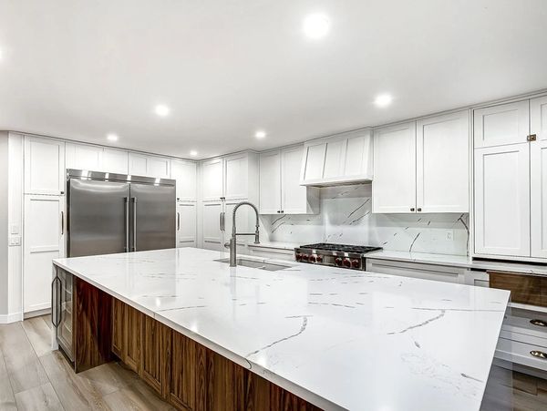 Modern kitchen with a large marble island and white cabinetry.