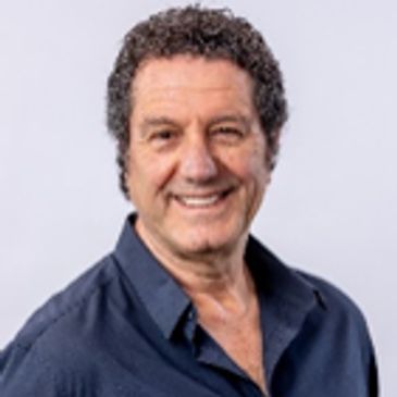 Smiling man with curly hair in a blue shirt.