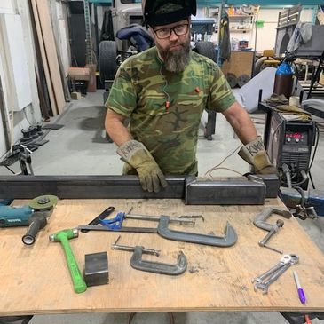 Man in a workshop with tools on a table.
