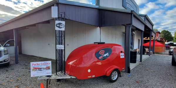 A red Wi-Fi hotspot trailer outside a building.