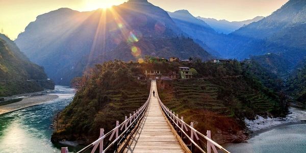 Sunset over a bridge leading to a village in the mountains.
