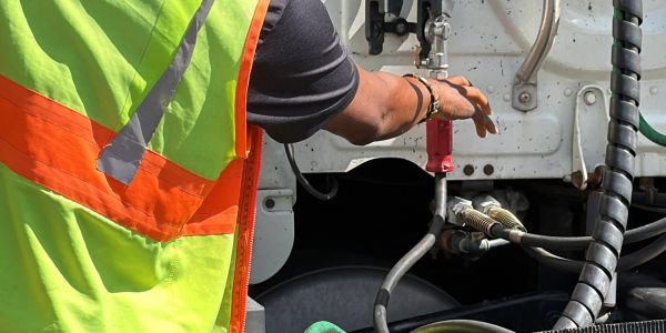 Person in a safety vest working on vehicle connections.
