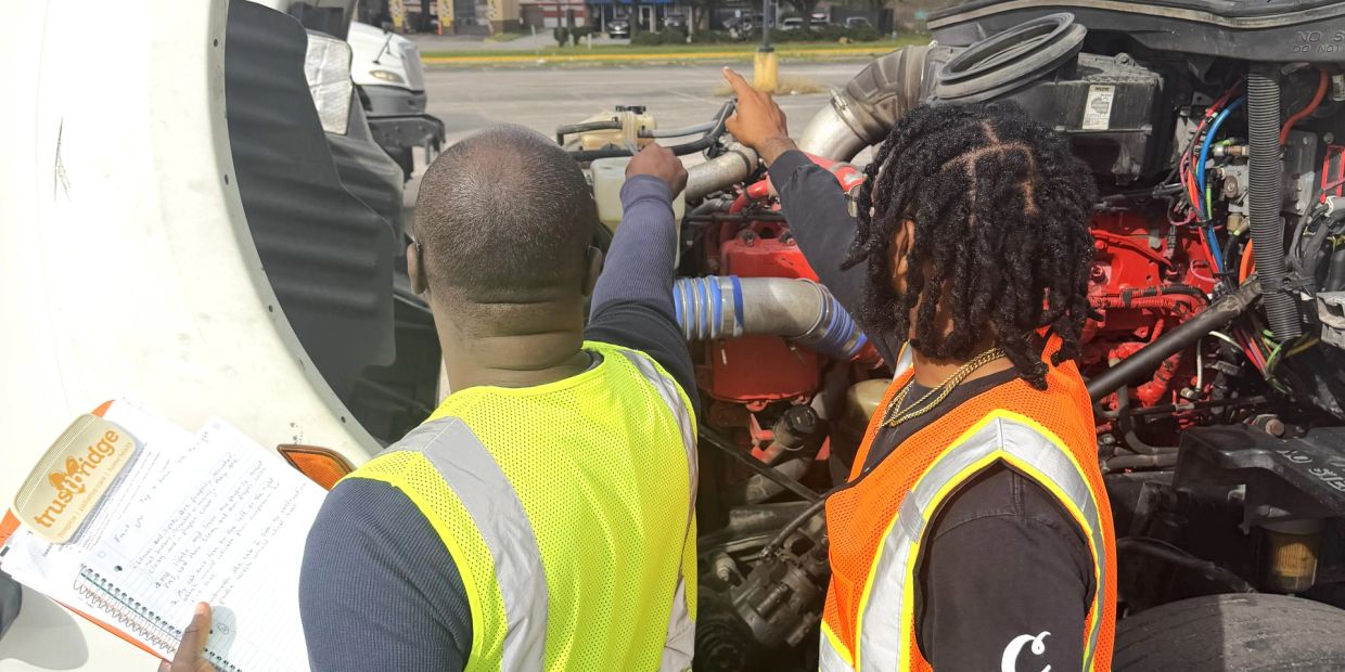 Two mechanics inspecting a truck engine.