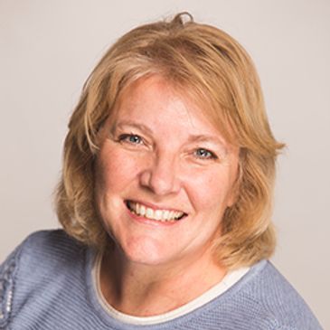 Blonde woman in blue shirt smiling at the camera