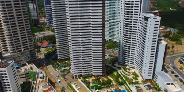 Aerial view of tall modern residential buildings with pools and greenery.