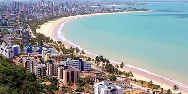 A coastal city with tall buildings along a curved sandy beach and turquoise ocean.