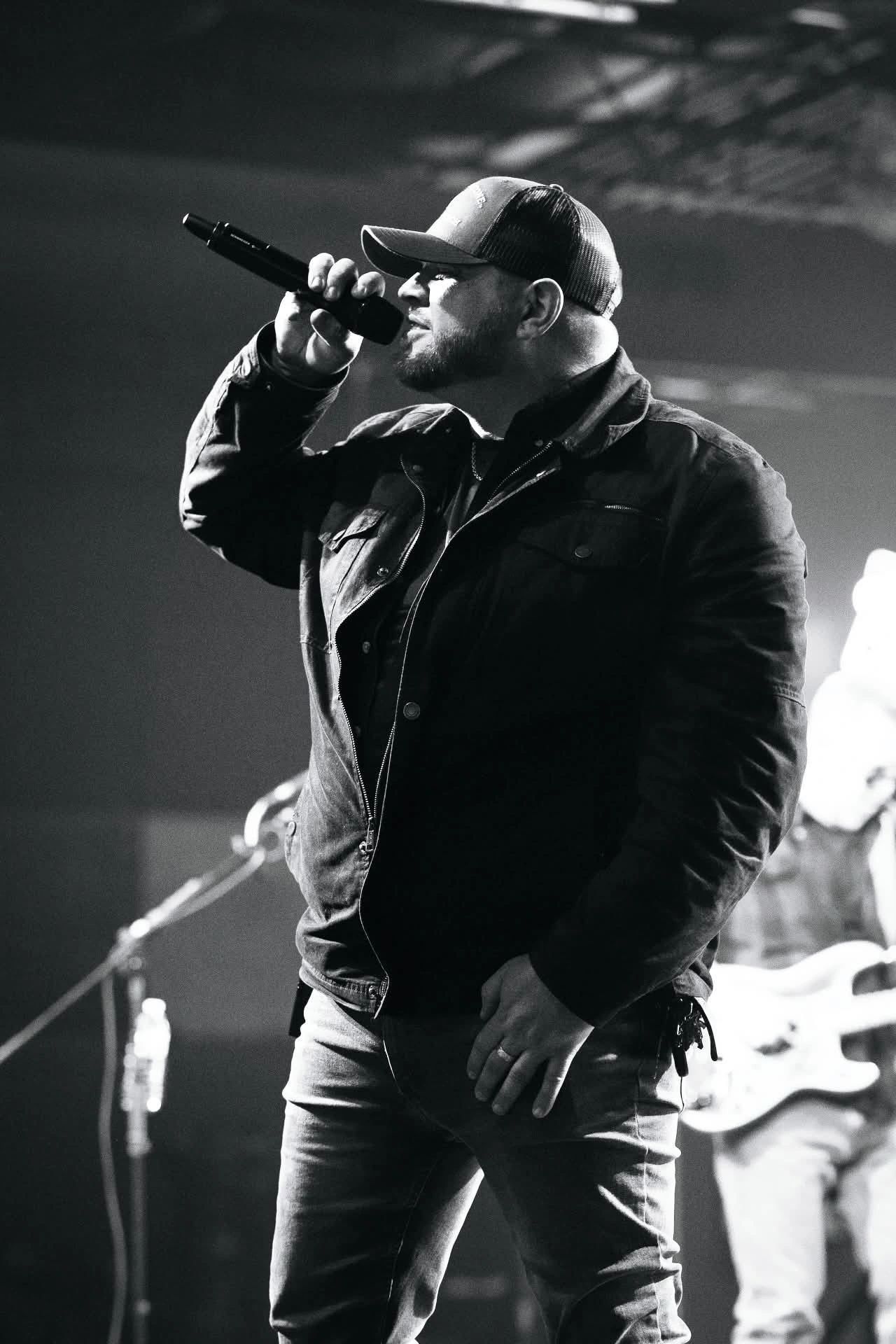 Black and white photo of a male singer passionately performing on stage.