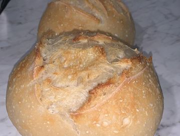 Two freshly baked crusty bread rolls on a marble surface.