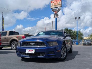 Blue Ford Mustang parked in a lot under a partly cloudy sky.