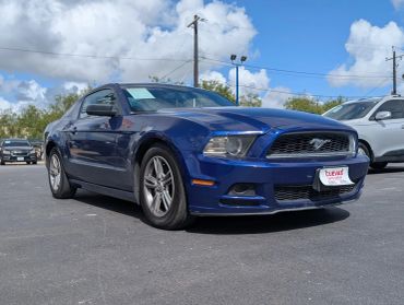 Blue Ford Mustang parked under a sunny sky.
