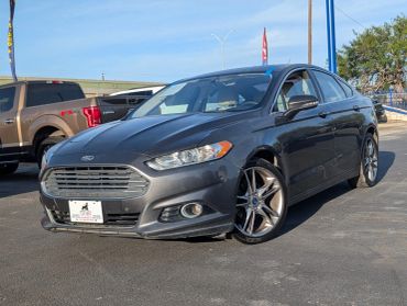 Gray Ford sedan parked outdoors under sunlight.