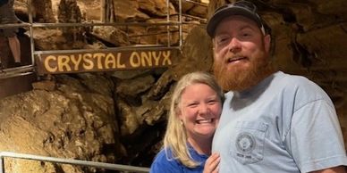 Smiling couple poses inside a cave near a Crystal Onyx sign.
