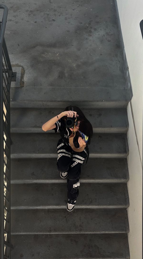Person sitting on stairs taking a photo with a camera.