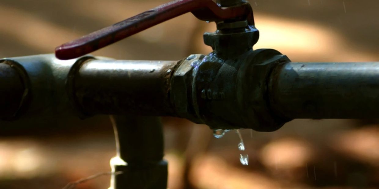 Close-up of a leaking metal water valve with drops falling.