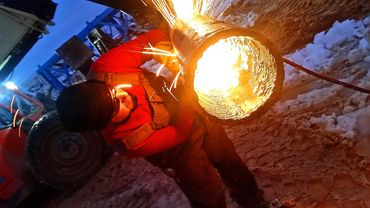 Man with torch cutting pipe in the evening, with sparks flying