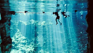 People swimming in a deep blue spring