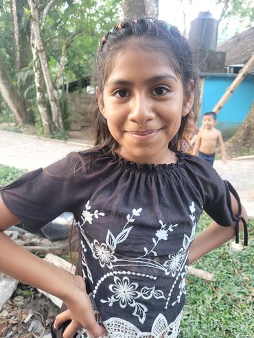 A smiling girl with a decorative shirt  and top braid